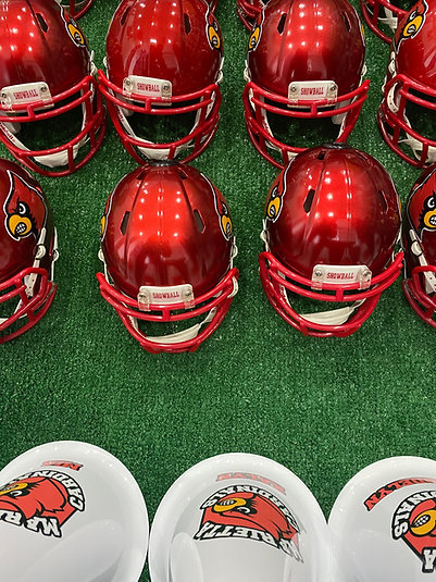 Rows of red Cardinals Showball mini helmets and branded shells staged on turf for a program order
